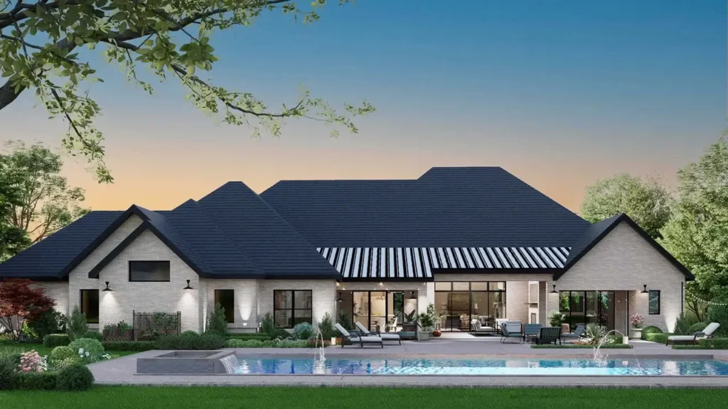 Rear view of the Hunters Glen house plan with illuminated covered patio, swimming pool, and outdoor entertaining area at dusk.